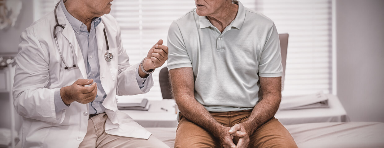 Doctor and senior male patient discussing complications and risks in hospital room Doctor and senior male patient discussing complications and risks in hospital room
