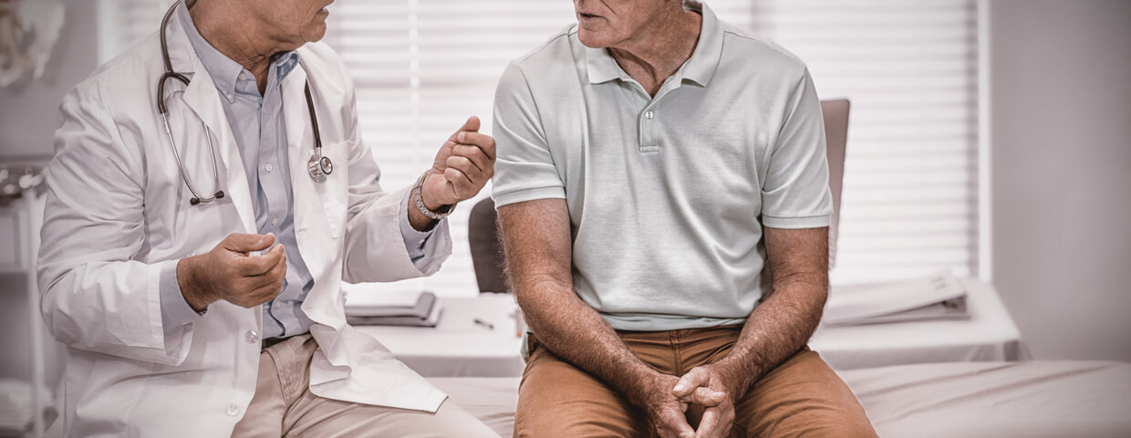 Doctor and senior male patient discussing complications and risks in hospital room