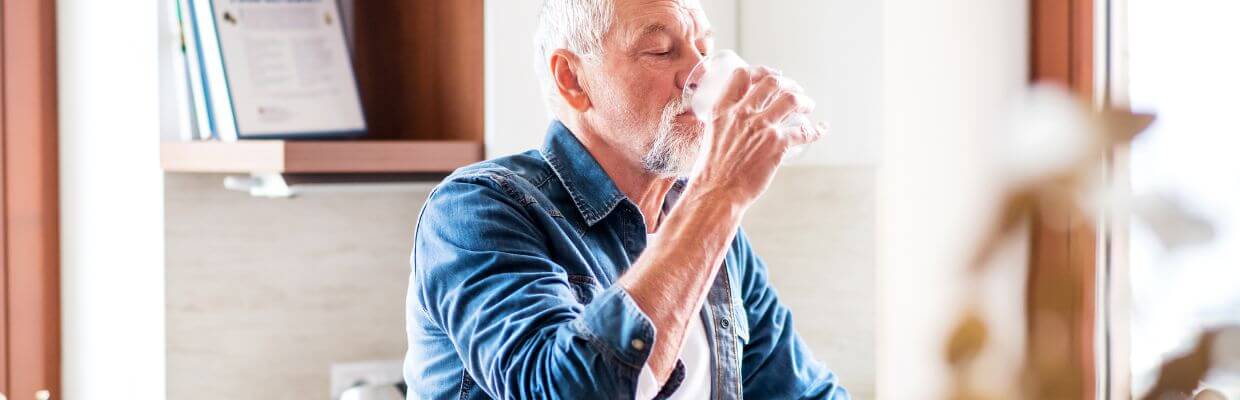 senior man drinking water out of a glass senior man drinking water out of a glass